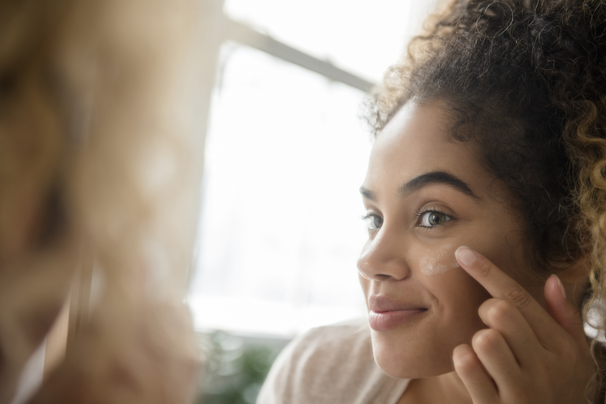A woman applying lotion to her face