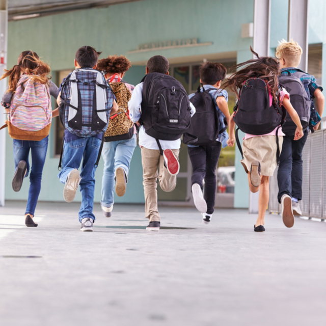 A group of kids running to a school entrance