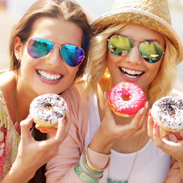 Ladies holding donuts and smiling