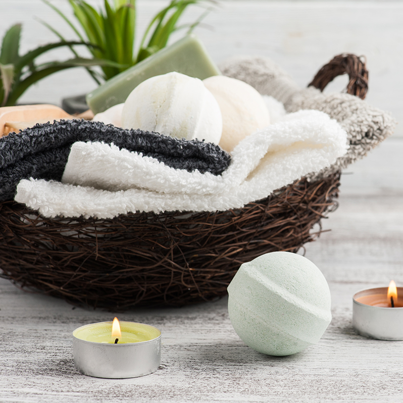 image of a candle, basked of towels, and bath bomb in a bathroom