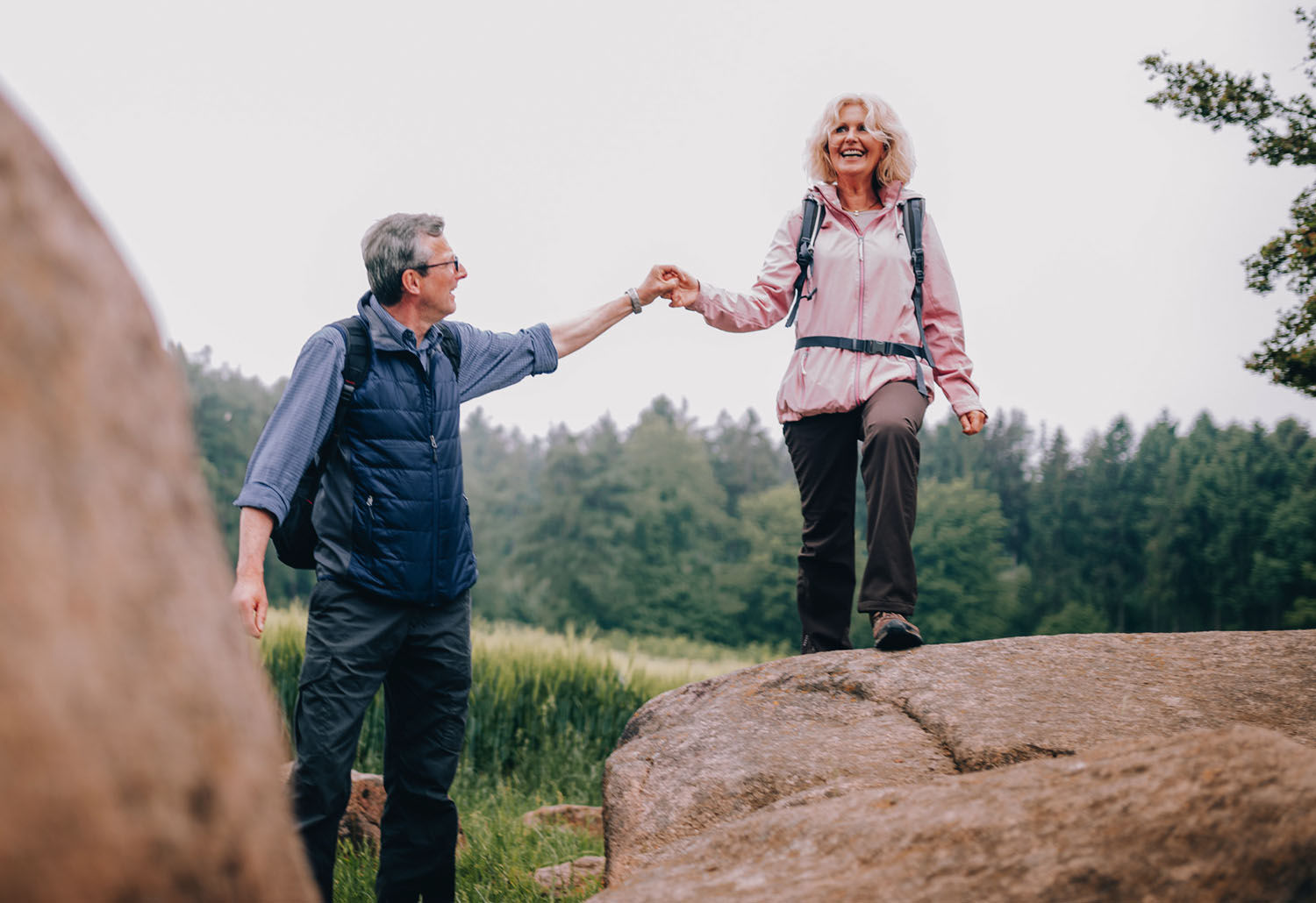 Older couple holding hands while climbing rocks