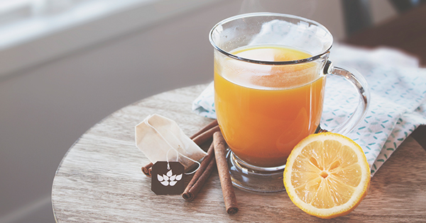 Ginger tea with lemon and cinnamon sitting next to it.