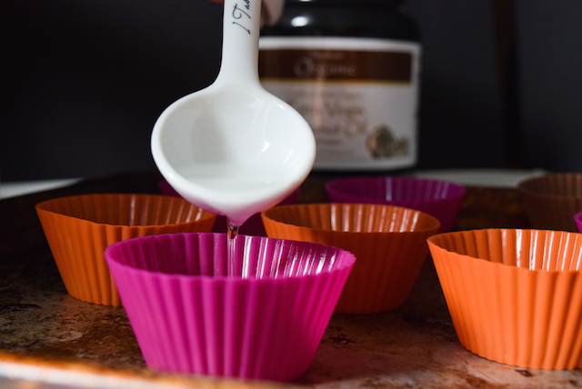 pouring melted coconut oil into silicon cup to freeze